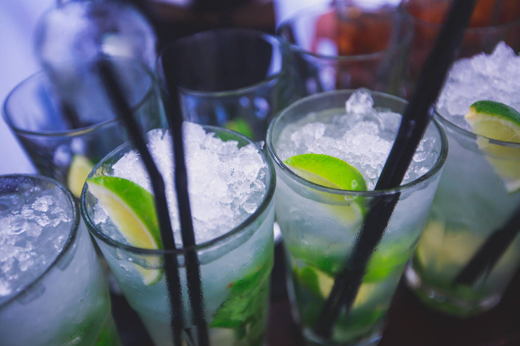 Mooie rijlijn cocktails van de verschillende gekleurde alcohol op een feestje, martini, wodka en anderen op ingerichte horeca boeket tafel op een openlucht evenement, foto met mooie bokeh - Foto, afbeelding