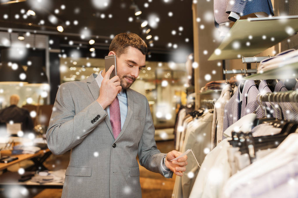 hombre feliz llamando en teléfono inteligente en la tienda de ropa
 - Foto, Imagen