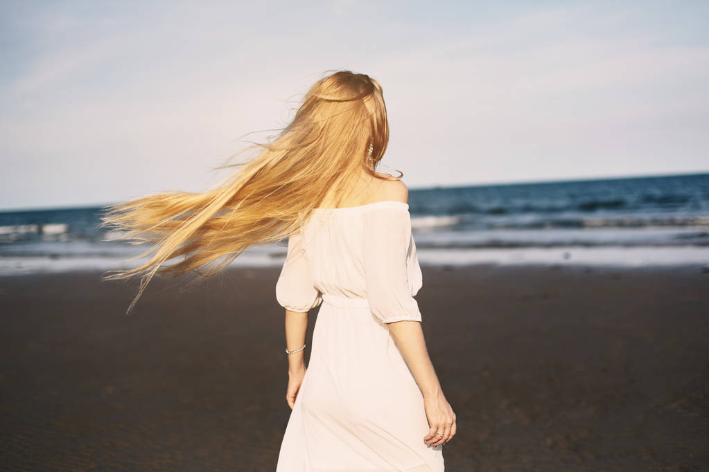 Mujer rubia en vestido blanco en la playa
 - Foto, imagen