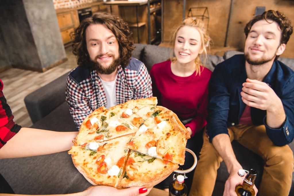 Amigos sonrientes degustando pizza
  - Foto, imagen