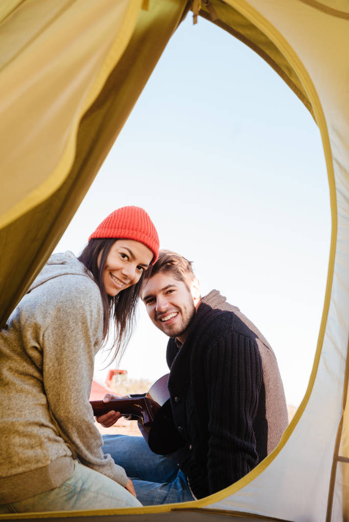 Happy νεαρό ζευγάρι στην αγάπη κάθονται μαζί στη σκηνή camping. - Φωτογραφία, εικόνα