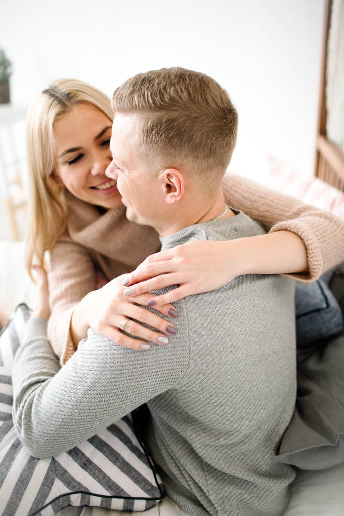 Joven hermosa pareja rubia oliendo feliz en la sala de estar
 - Foto, Imagen