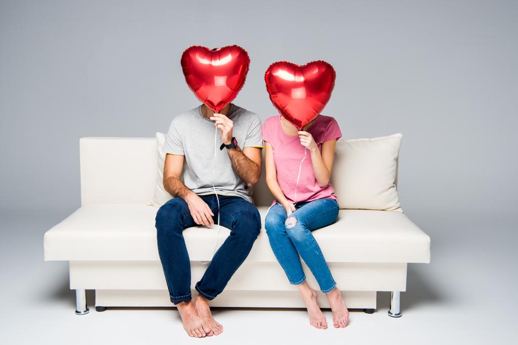 Couple assis sur le canapé avec des ballons rouges
 - Photo, image