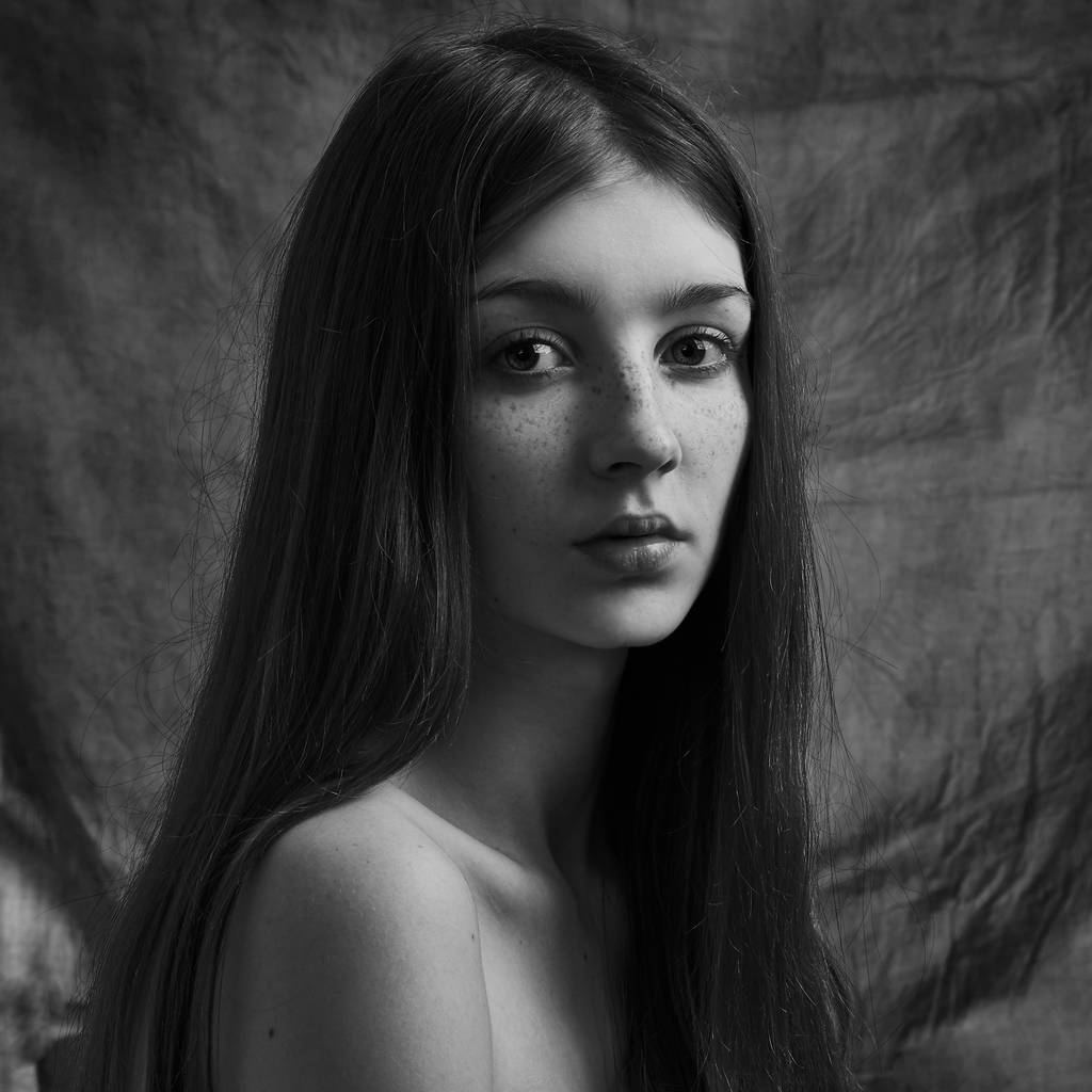 Retrato dramático en blanco y negro de una hermosa chica solitaria con pecas aisladas sobre un fondo oscuro en un plano de estudio - Foto, Imagen