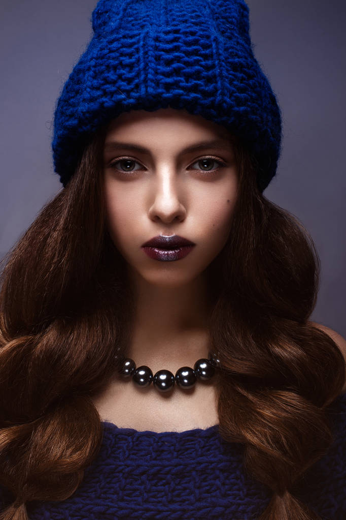Belle fille en hiver tricot chapeau de couleur bleue avec un collier autour du cou de perles. Jeune modèle avec maquillage doux et lèvres argentées
. - Photo, image