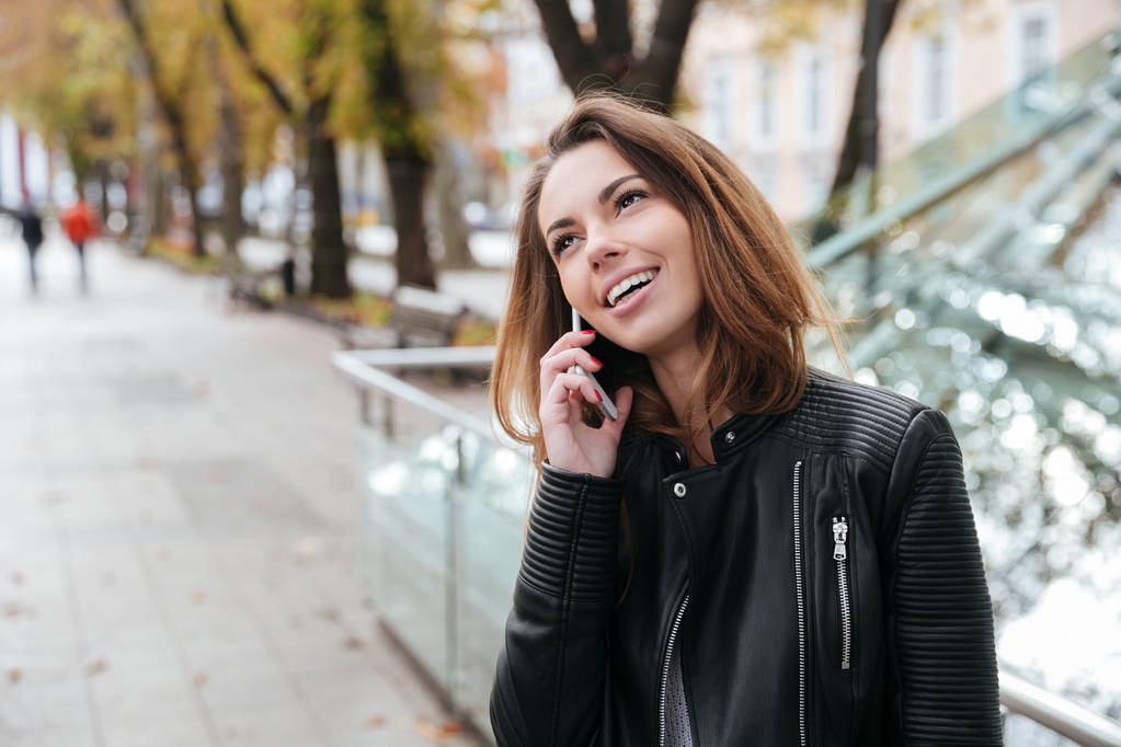 Ayakta ve şehrin cep telefonuyla konuşan kadın - Fotoğraf, Görsel