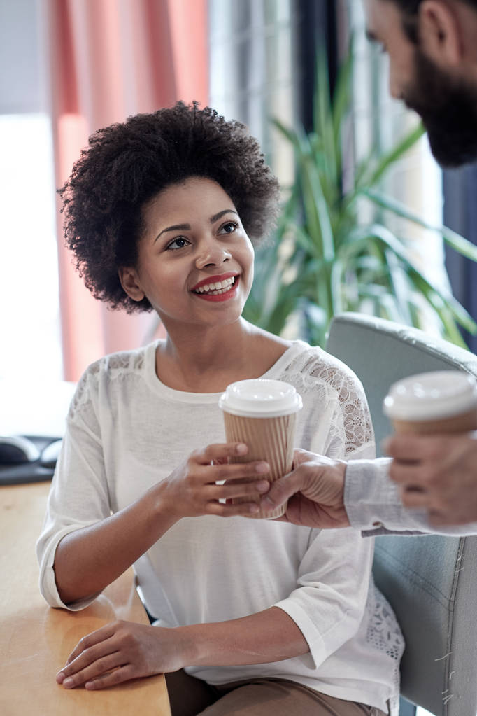 happy woman taking coffee from man in office - Photo, Image