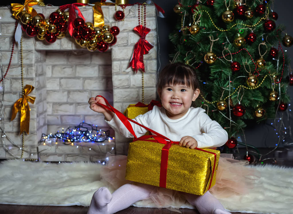 Маленька дівчинка розкриває подарунок. Різдвяні сцени
. - Фото, зображення
