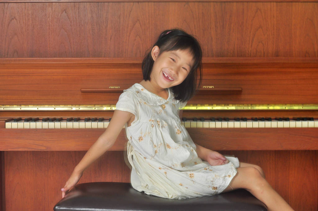 asian child sits in front of the piano - Photo, Image