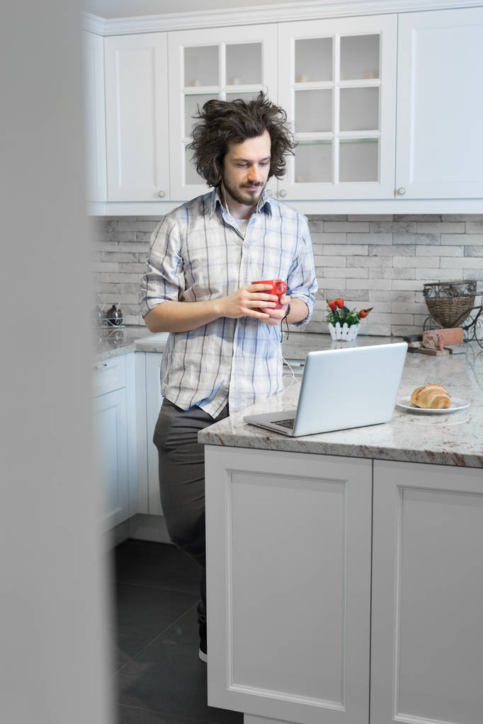 Homem comendo café da manhã durante o uso de laptop
 - Foto, Imagem