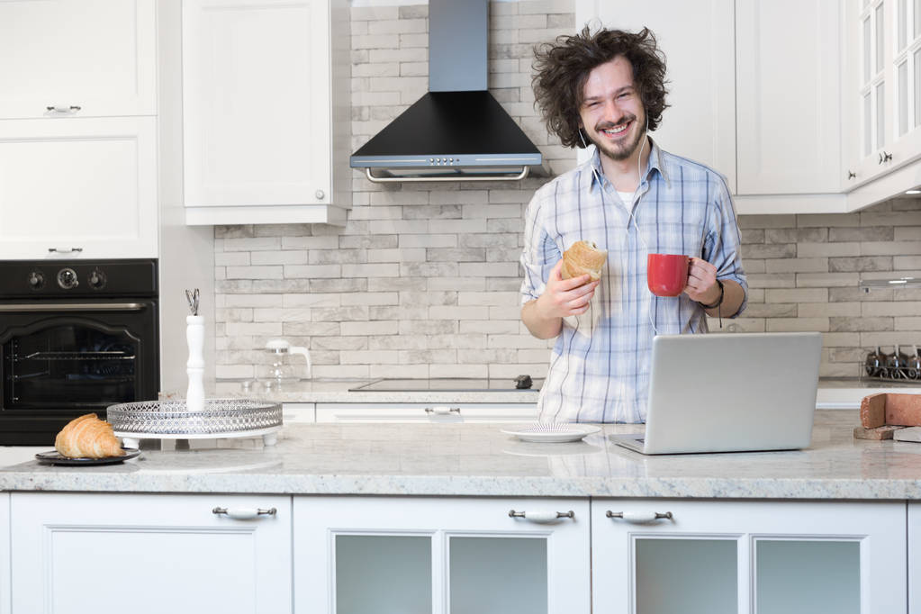 Людина їсть сніданок під час використання ноутбука
 - Фото, зображення
