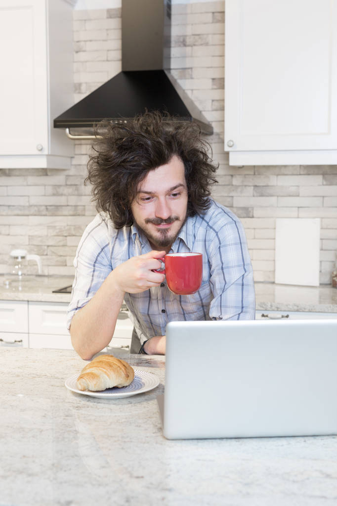 Mężczyzna jedzenie śniadanie podczas przy pomocy laptopa - Zdjęcie, obraz