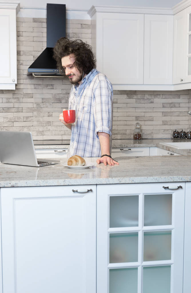 Homem comendo café da manhã durante o uso de laptop
 - Foto, Imagem
