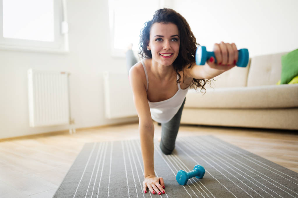 Sportliche Frau trainiert zu Hause, um fit zu bleiben - Foto, Bild
