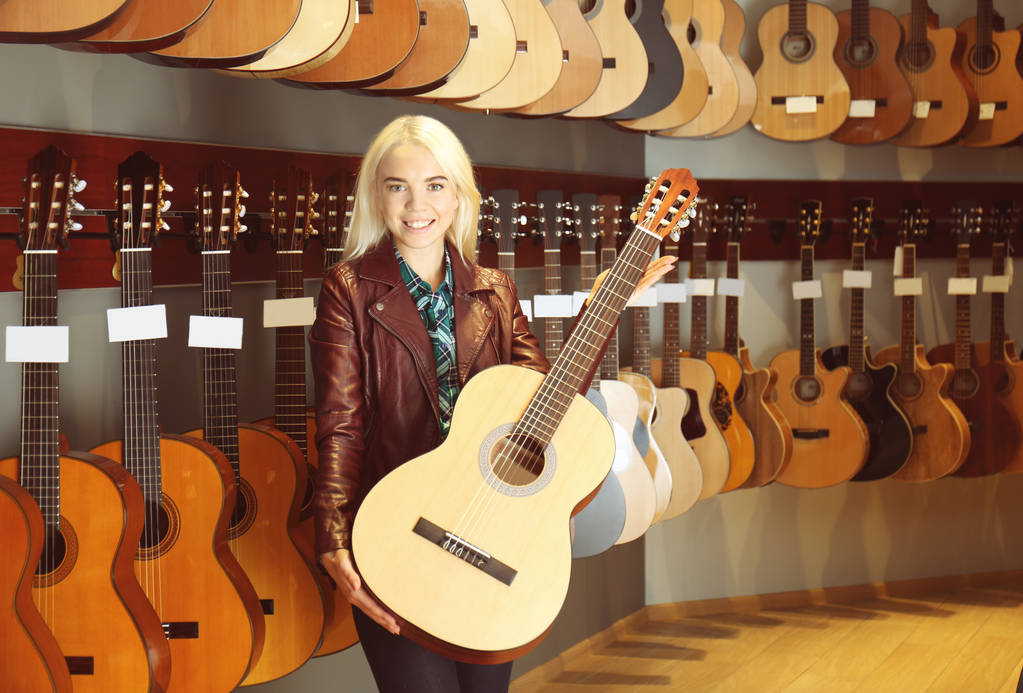 Női elárusítónő gazdaság gitár bolt - Fotó, kép