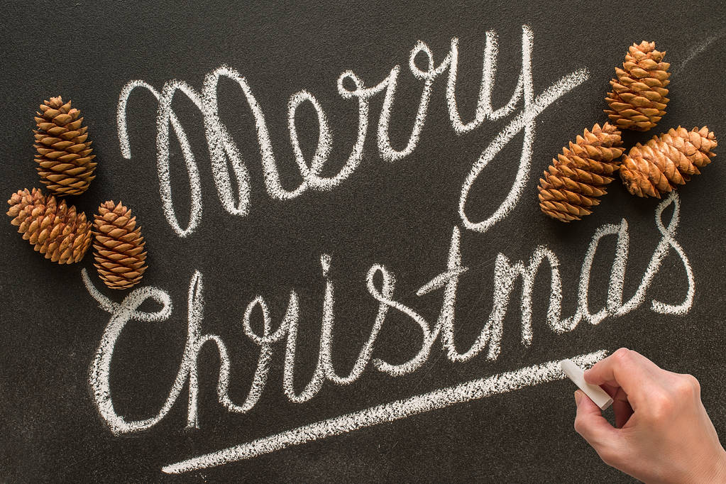 Χαρούμενα Χριστούγεννα χέρι γράφει στον πίνακα κιμωλίας.  - Φωτογραφία, εικόνα