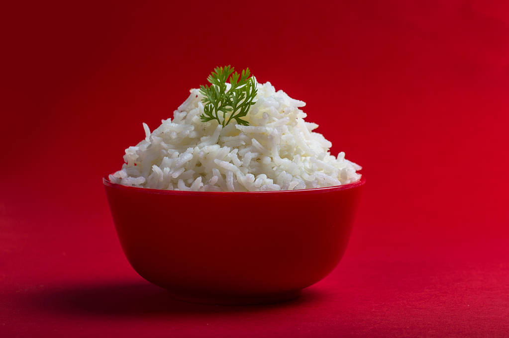Kırmızı bir arka plan üzerinde kırmızı bir kasede düz beyaz basmati pirinç pişmiş - Fotoğraf, Görsel