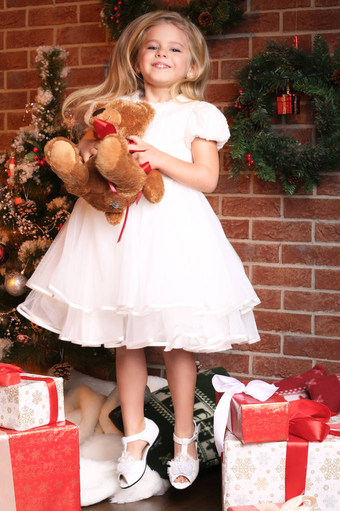 Meisje springen in de buurt van de gaven en de kerstboom - Foto, afbeelding