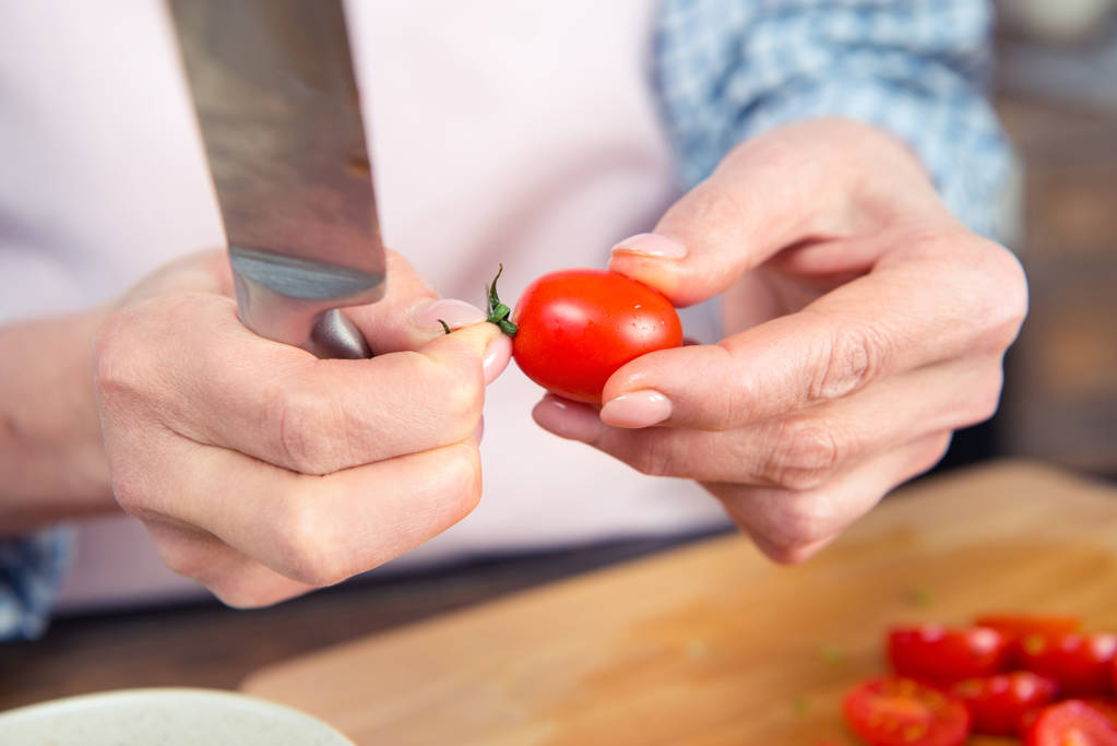 Жінка тримає ніж і помідор
 - Фото, зображення