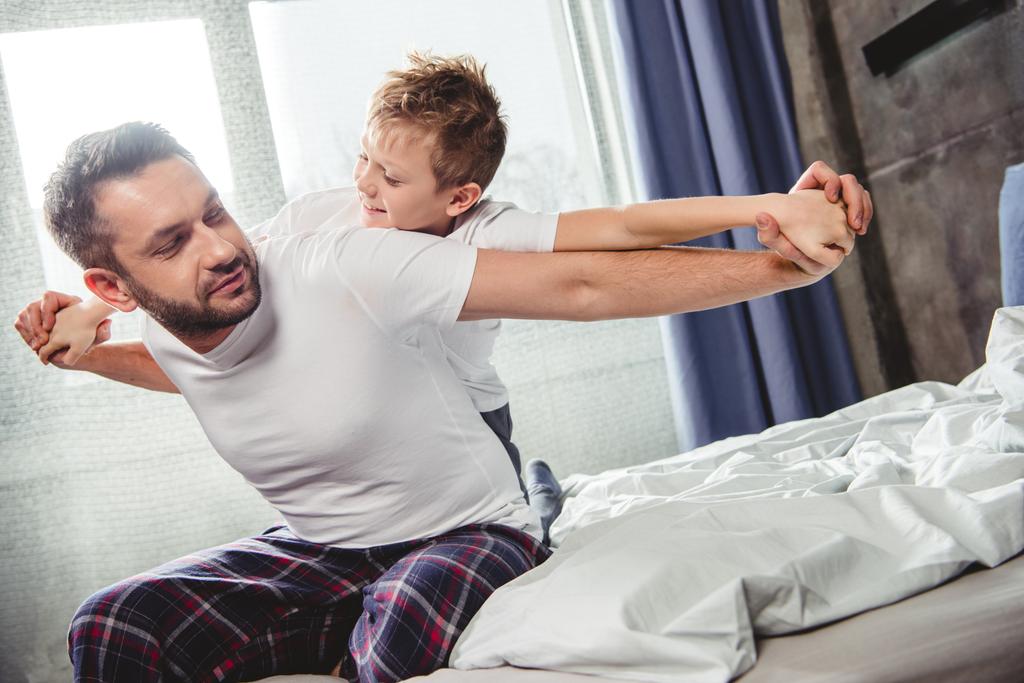 Gelukkig vader en zoon op bed  - Foto, afbeelding