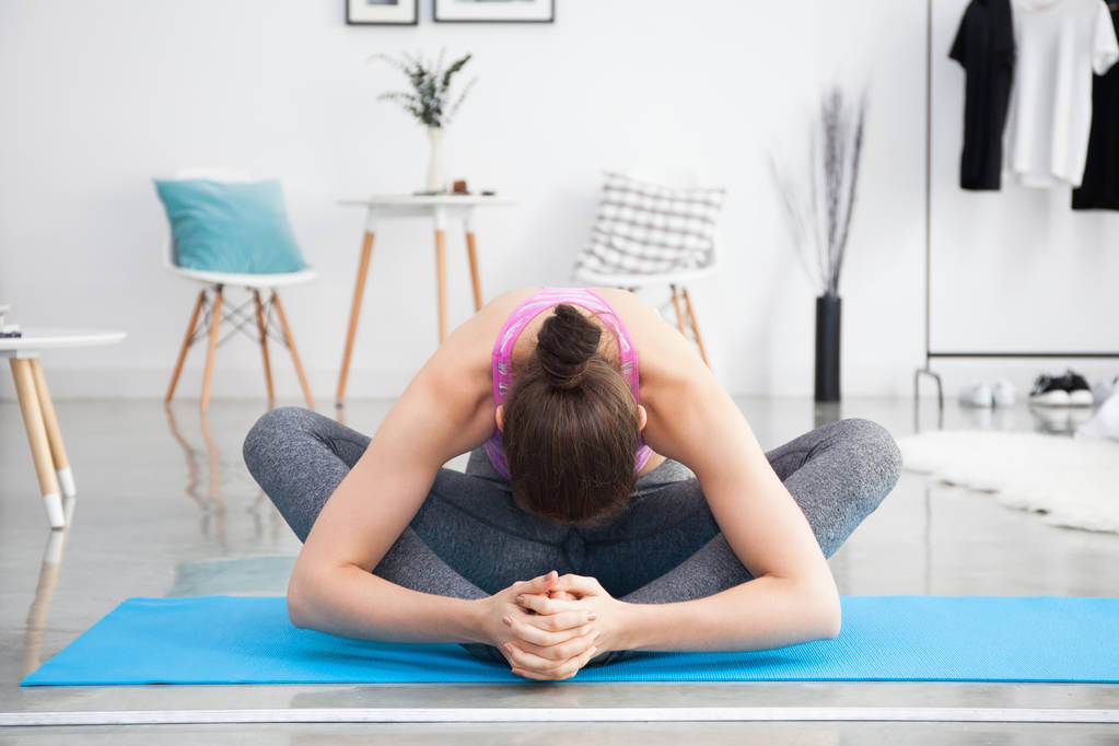 Joven mujer caucásica estirándose y haciendo yoga en casa
 - Foto, imagen