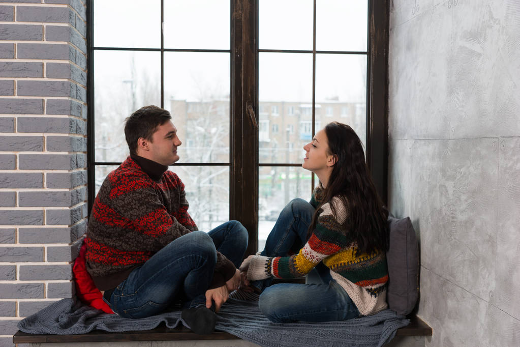 Young couple in warm knitted sweaters talking while sitting on t - Photo, Image