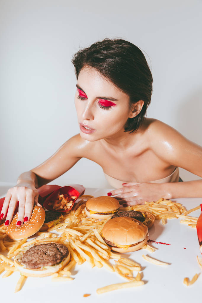 Attrayant jeune femme avec un maquillage lumineux manger restauration rapide
 - Photo, image