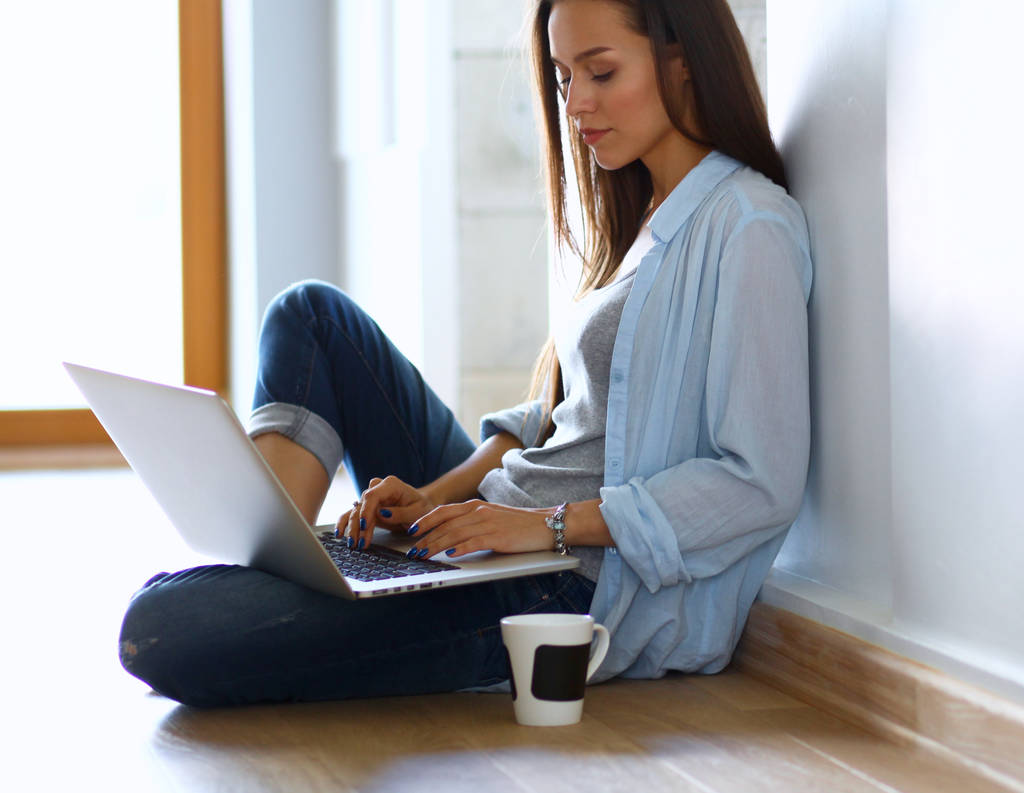 Молодая красивая женщина дома сидит на полу с ноутбуком
 - Фото, изображение