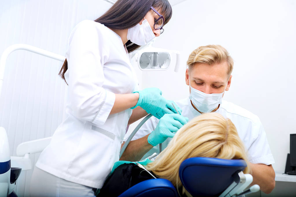 Zahnarzt-Mann mit Assistentin behandelt Zahnpatient im Krankenhaus - Foto, Bild
