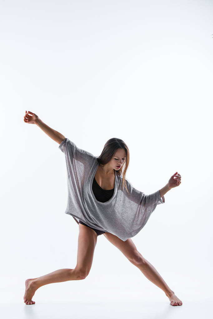 Jovem dançarina bonita em vestido bege dançando no fundo branco
 - Foto, Imagem