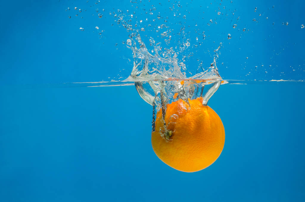 Oranssi roiskeita vedessä sinisellä pohjalla
 - Valokuva, kuva