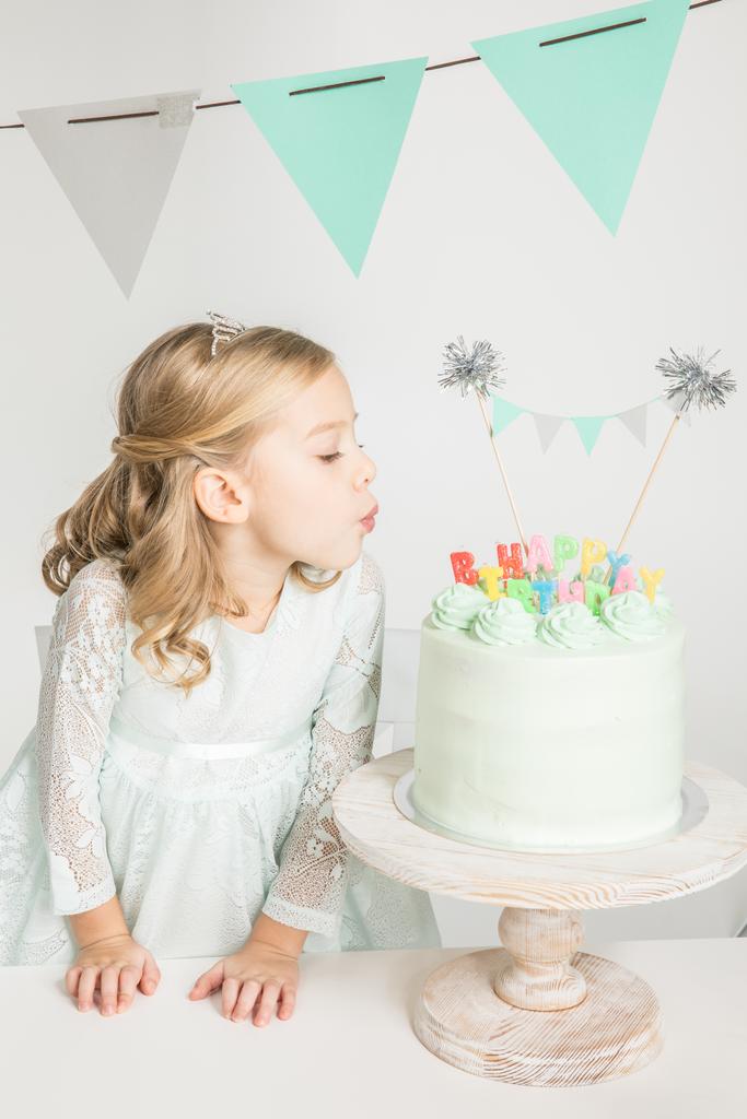 Dziewczyna dmuchanie na tort urodzinowy - Zdjęcie, obraz