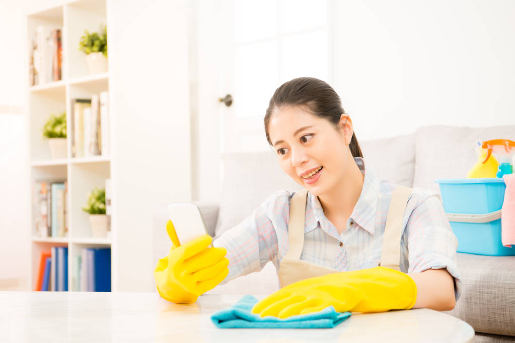pulizia donna e utilizzando uno smartphone
  - Foto, immagini