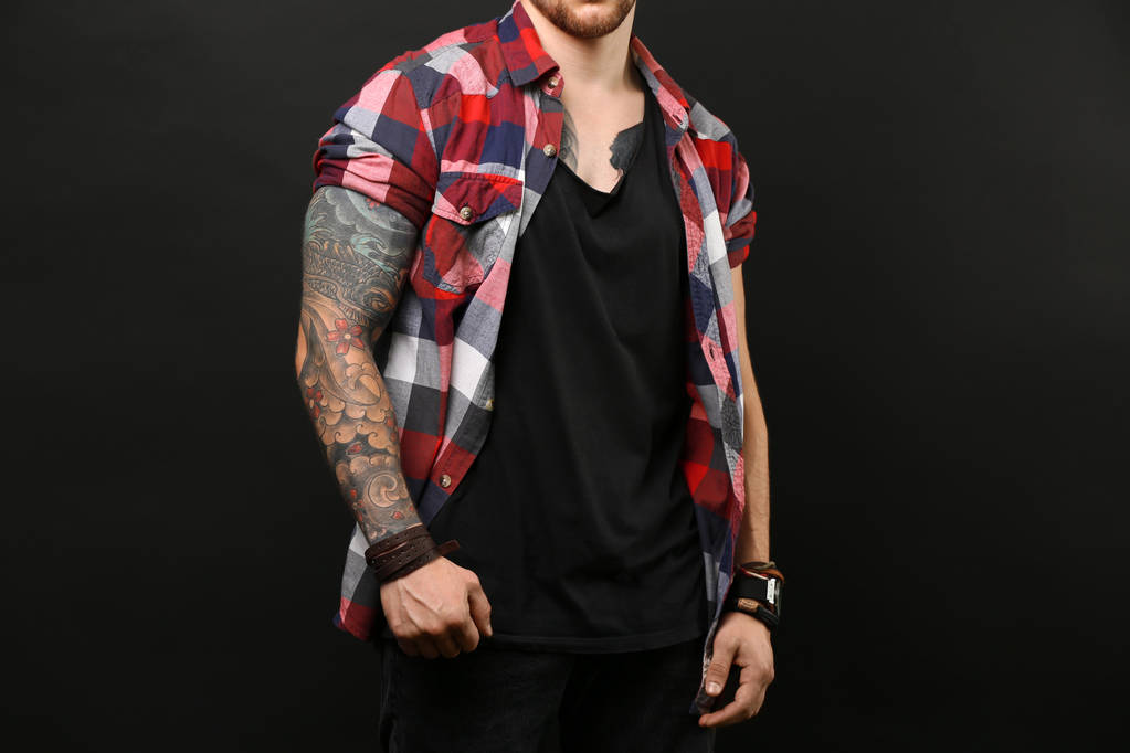 Tetovált fiatalember pózol a sötét háttér - Fotó, kép