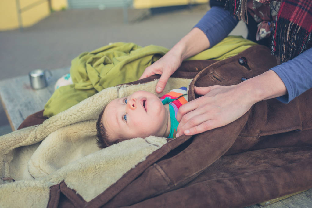 Egy fiatal anya a csomagolás kisbabáját egy kabátot a kívülre - Fotó, kép