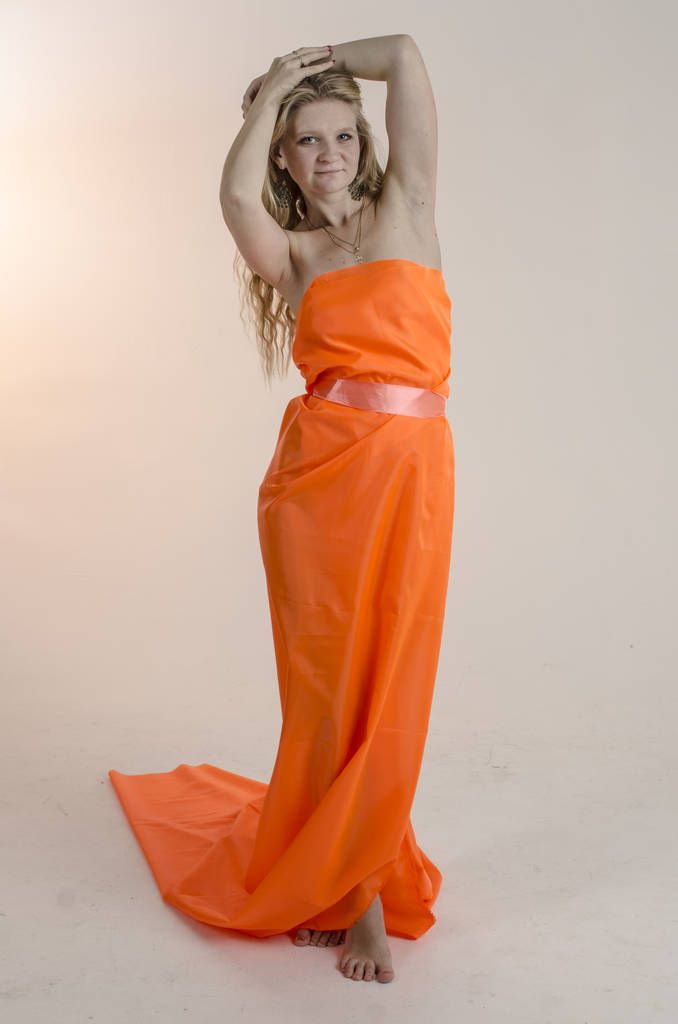 Young beautiful blonde woman in a bright orange fabric in a dress - Photo, Image