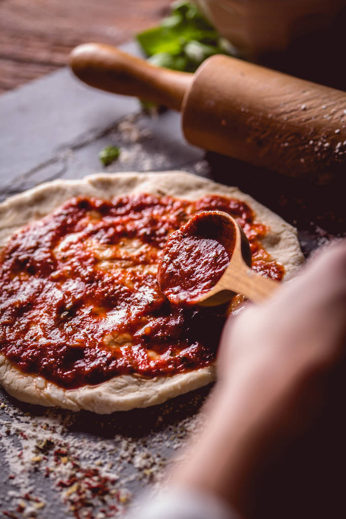 Fille place la sauce tomate sur la pizza fraîche
 - Photo, image