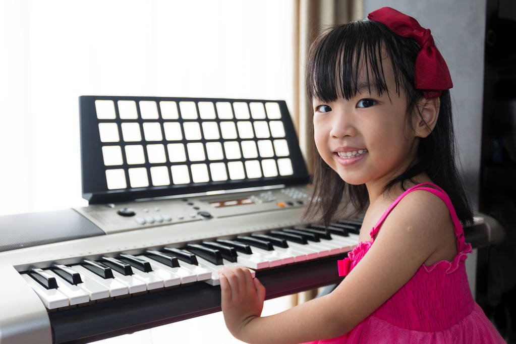 Happy Asian Chinese little girl playing electric piano keyboard  - Photo, Image