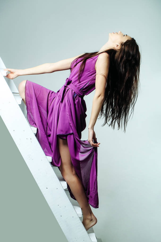 mooie vrouw op ladder in jurk - Foto, afbeelding