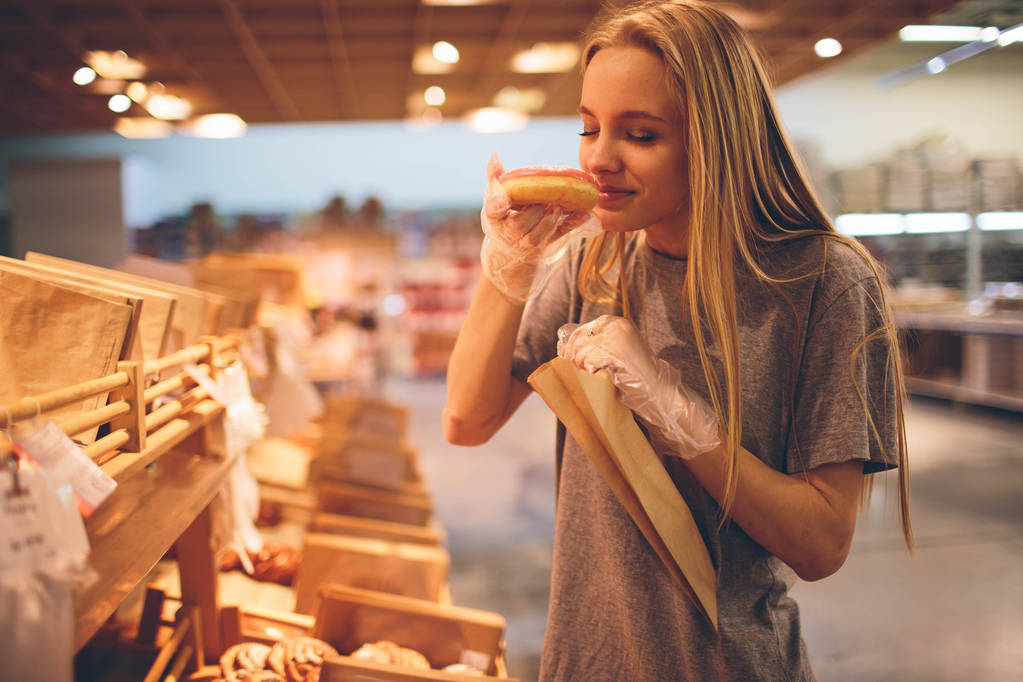 若い女性は店でパンを選ぶ - 写真・画像