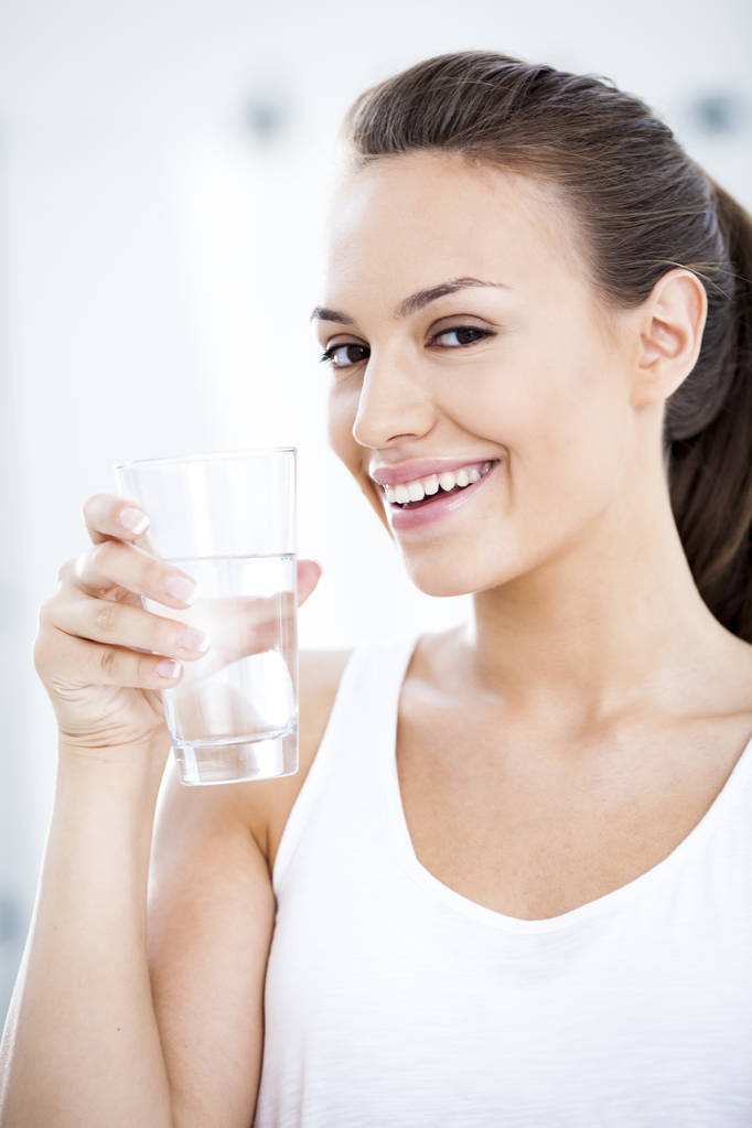 молодая женщина со стаканом воды - Фото, изображение