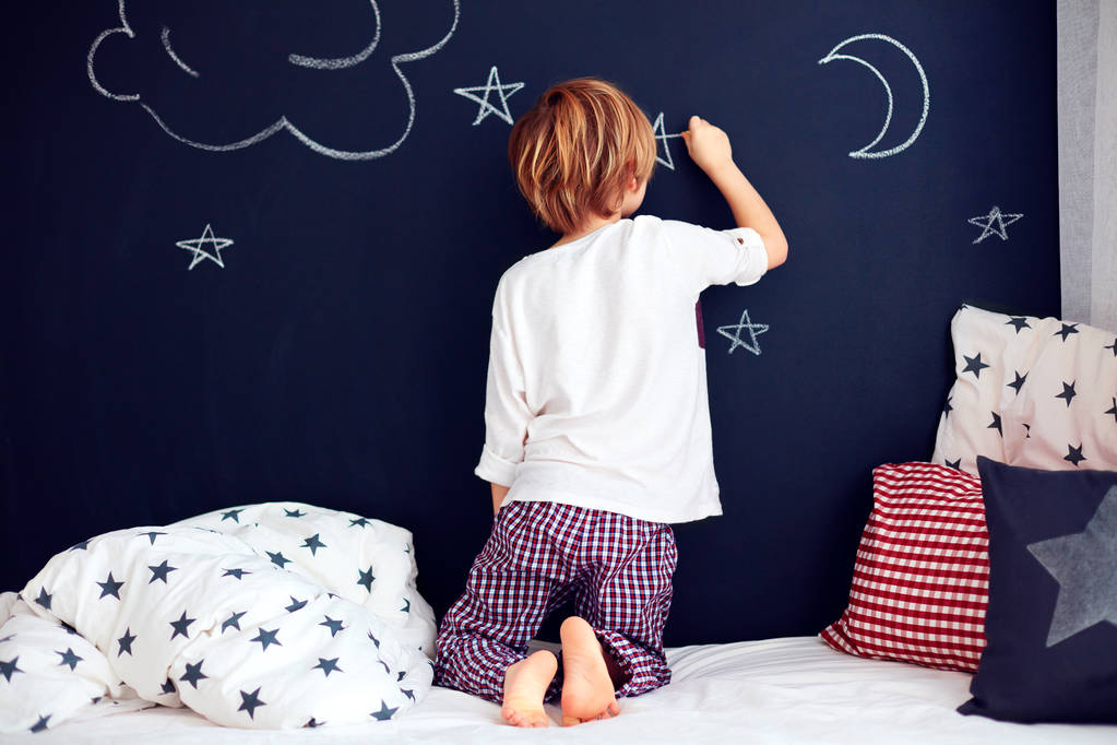 niedliches Kind im Pyjama bemalt Kreidewand in seinem Schlafzimmer - Foto, Bild