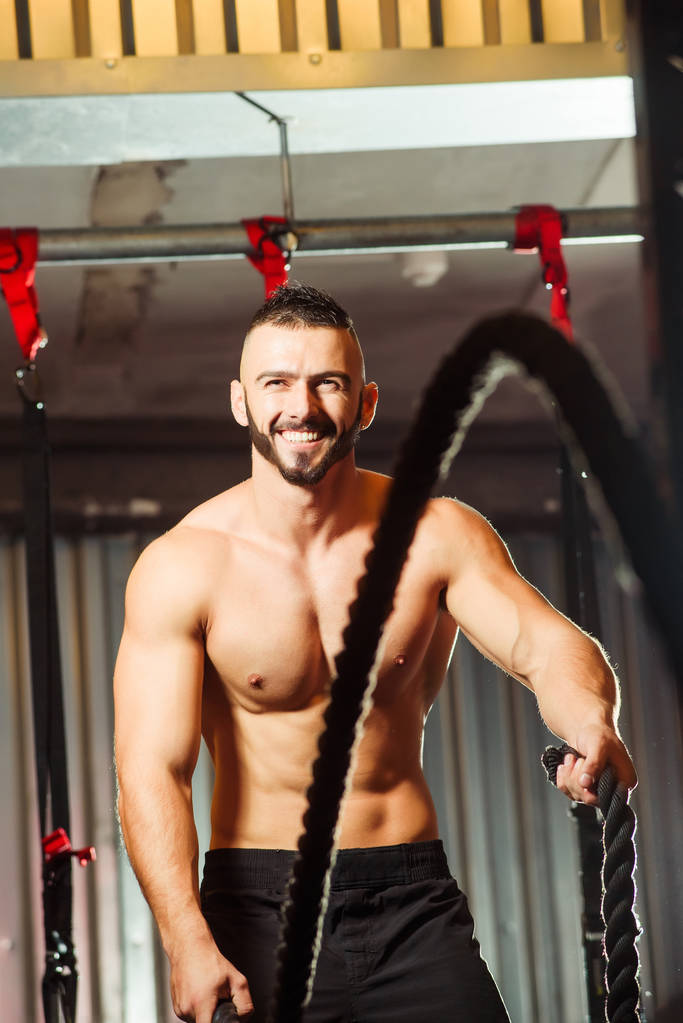 Jeune homme en forme faisant de l'exercice avec des cordes de combat dans la salle de fitness
 - Photo, image