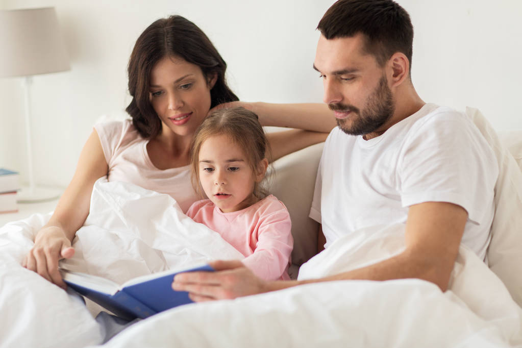 щаслива сім'я читає книгу в ліжку вдома
 - Фото, зображення