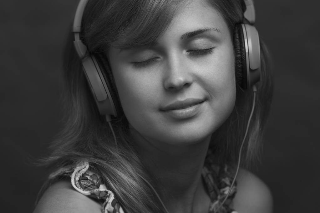 Porträt einer Frau mit Kopfhörer, die Musik hört - Foto, Bild