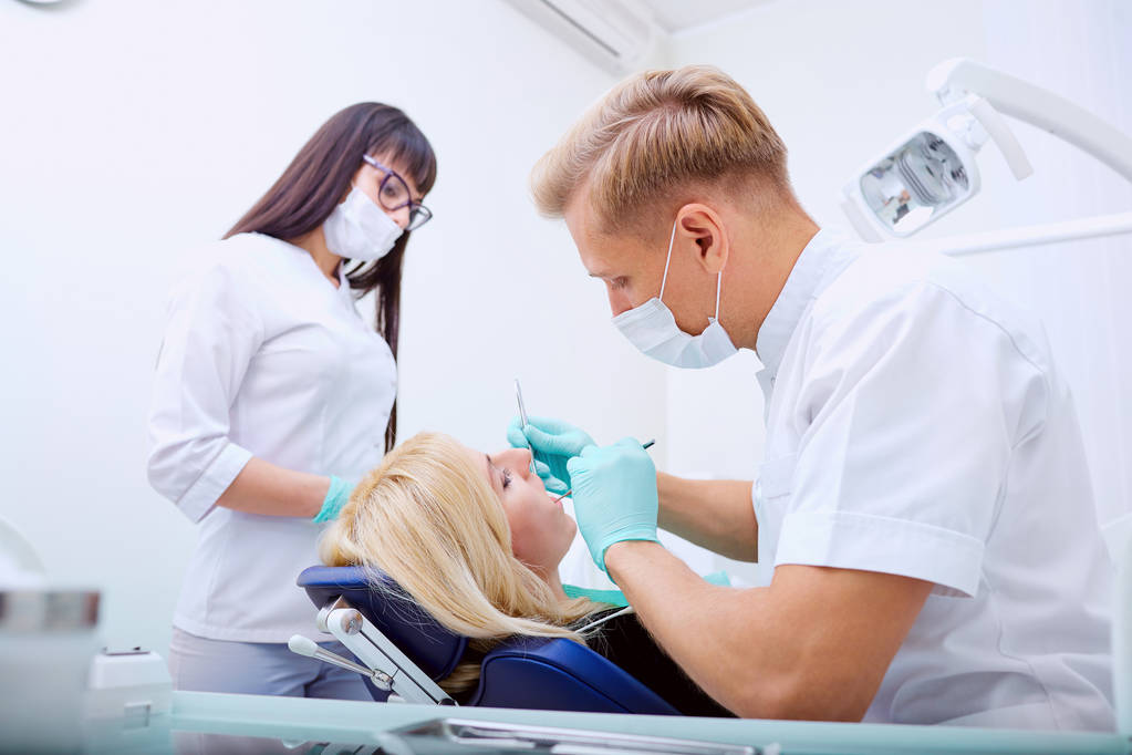 Człowiek dentysta z asystentem leczy zęby pacjenta w szpitalu ofi - Zdjęcie, obraz