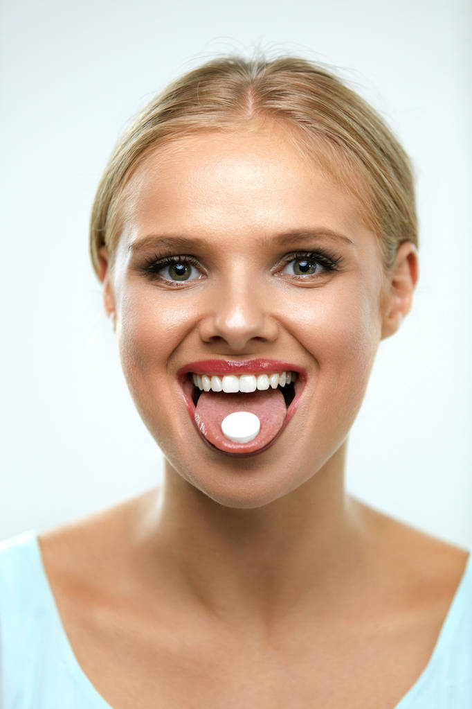 Hermosa mujer sonriente tomando medicina, sosteniendo la píldora en la lengua
 - Foto, imagen