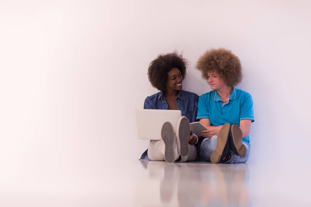 mnohonárodnostní pár sedí na podlaze s notebooku a tabletu - Fotografie, Obrázek