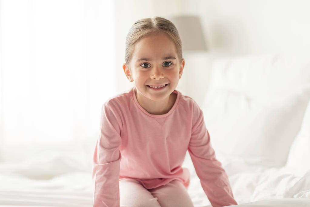 onnellinen pieni tyttö sängyssä kotona makuuhuoneessa
 - Valokuva, kuva