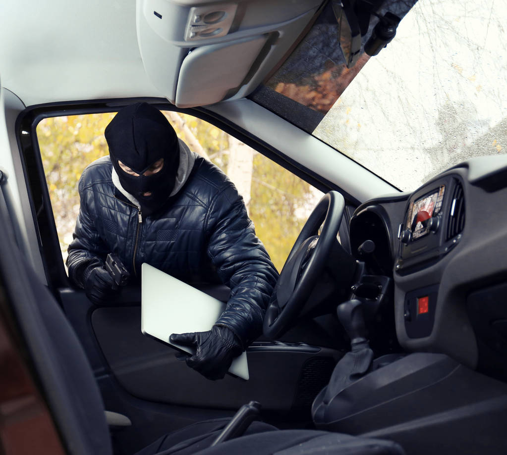 Κλέφτης στη μάσκα κλοπή φορητού υπολογιστή από ένα αυτοκίνητο - Φωτογραφία, εικόνα